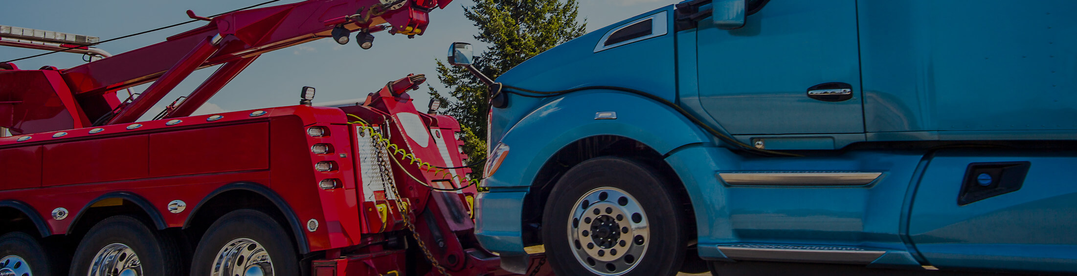 Blue semi tractor hooked to a red tow truck